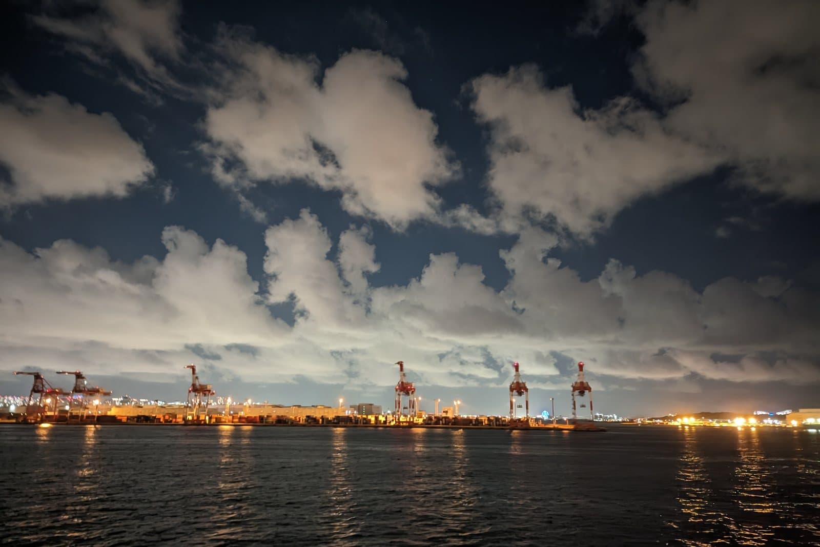 Container terminal gantry cranes on the waterfront at dusk.