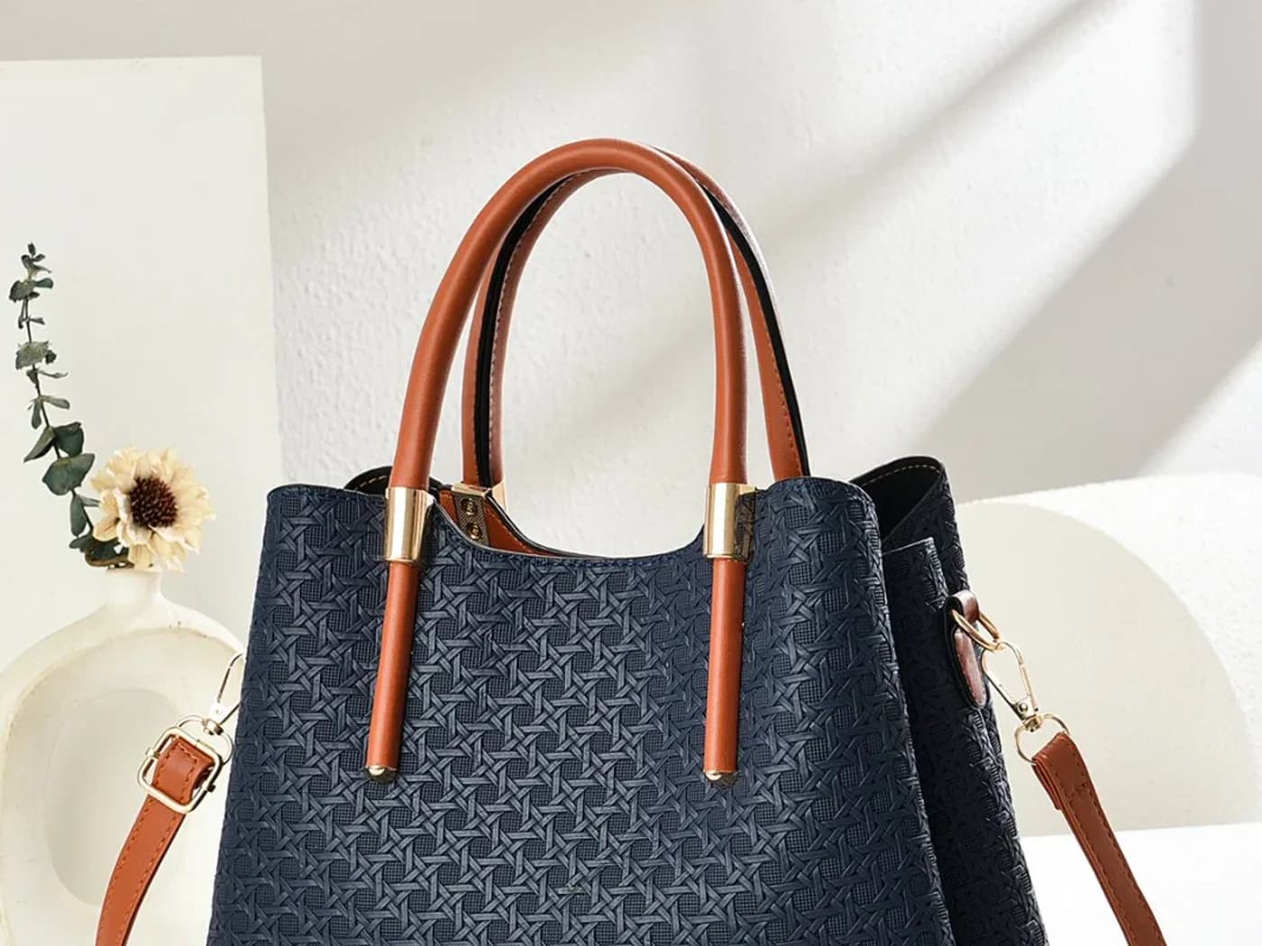 Navy woven large capacity handbag with brown handles and shoulder strap.