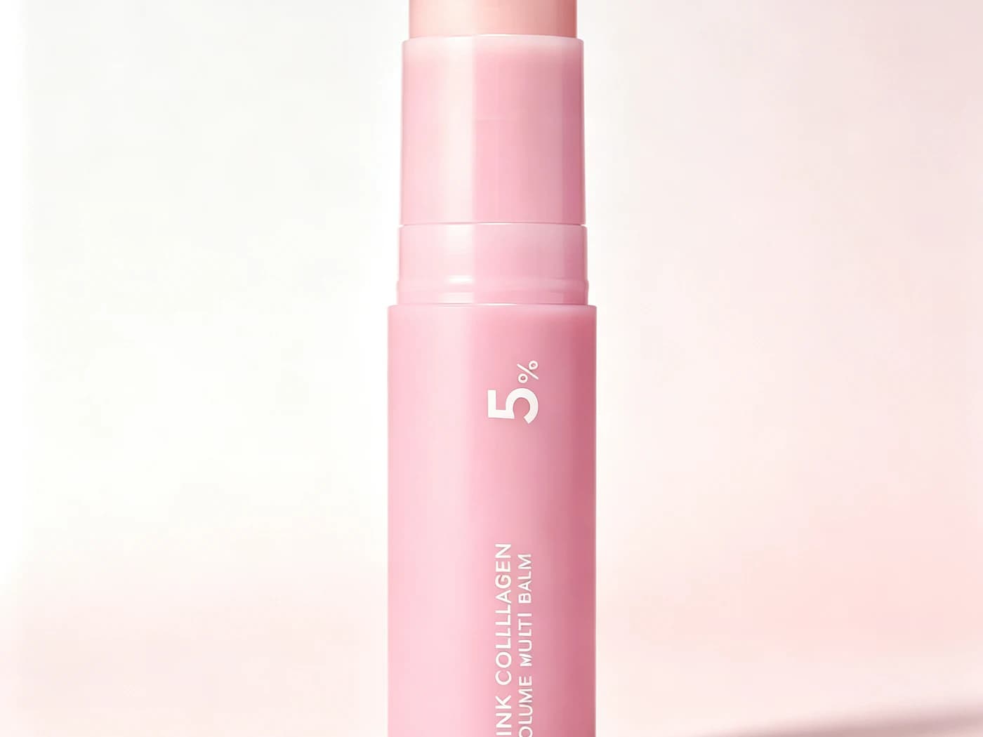 Pink skincare balm stick displayed against a soft pink background.